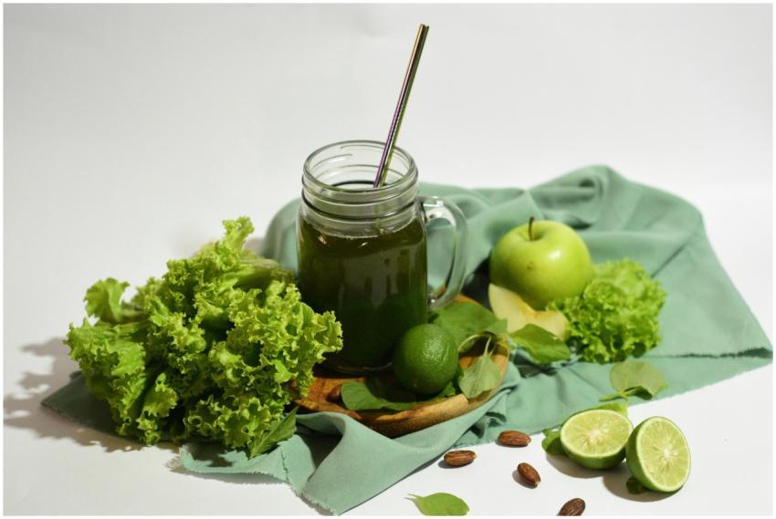 A vibrant green juice surrounded by fresh apples,