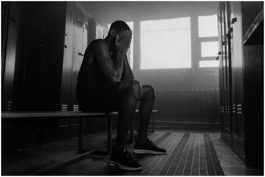 Monochrome image of a man sitting in a locker room