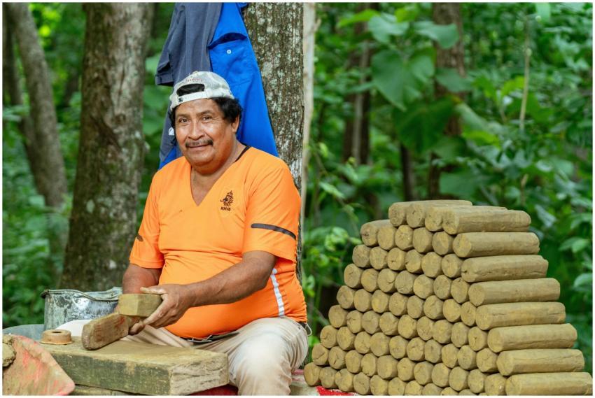 Adult man crafting adobe bricks in a lush forest e
