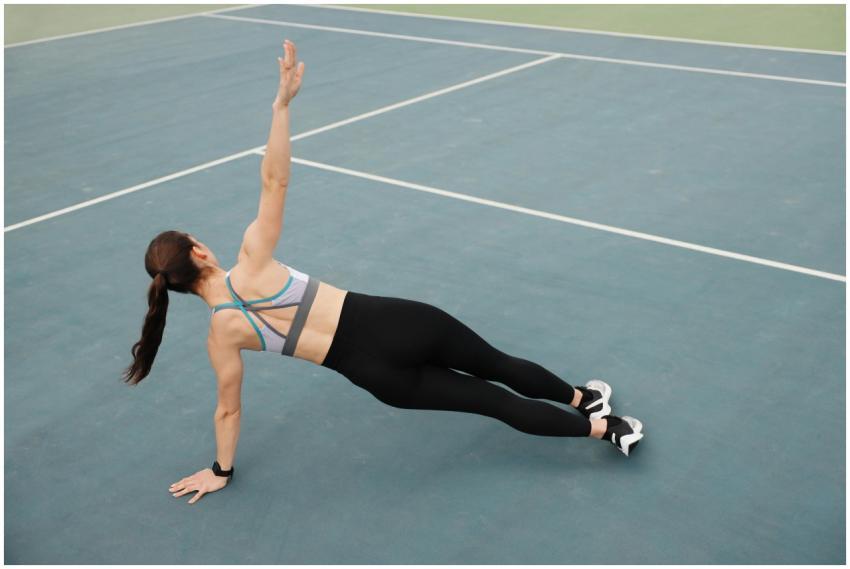 Woman in activewear doing a side plank on a tennis
