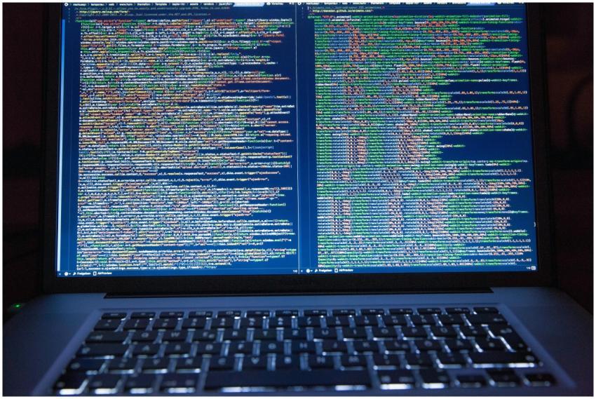 Laptop displaying source code with dual screens fo