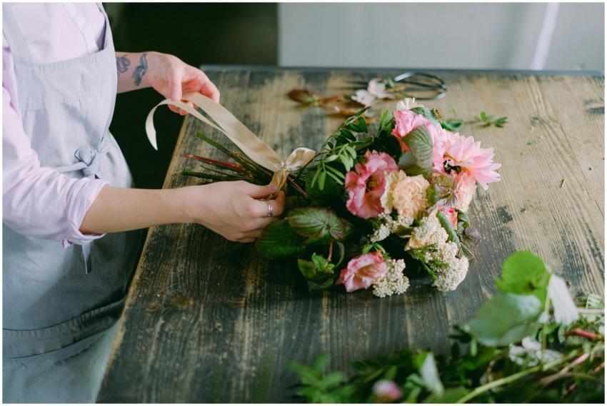 Florist tying ribbon on a vibrant flower bouquet o