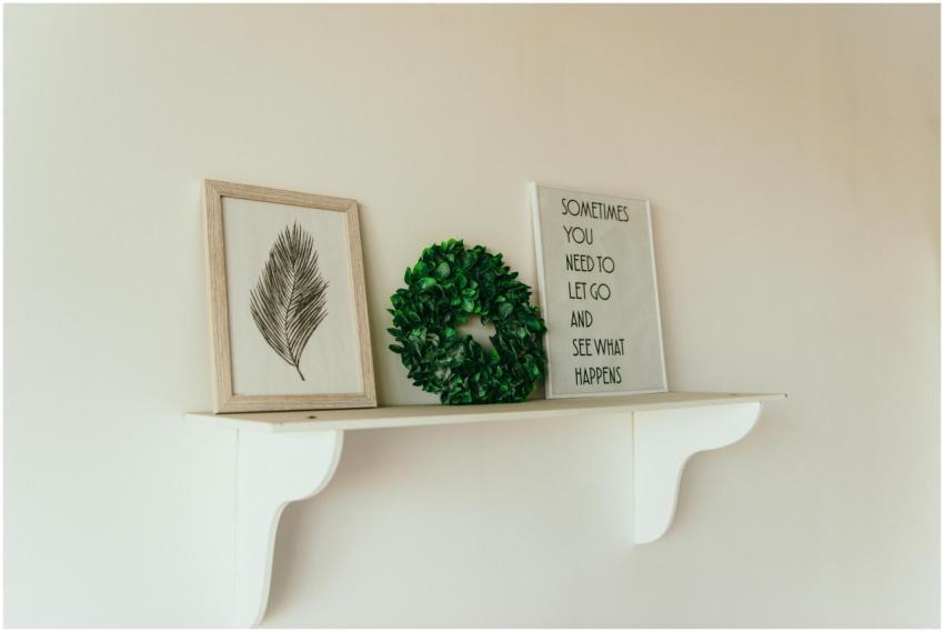 A minimalist shelf with framed art, a green wreath