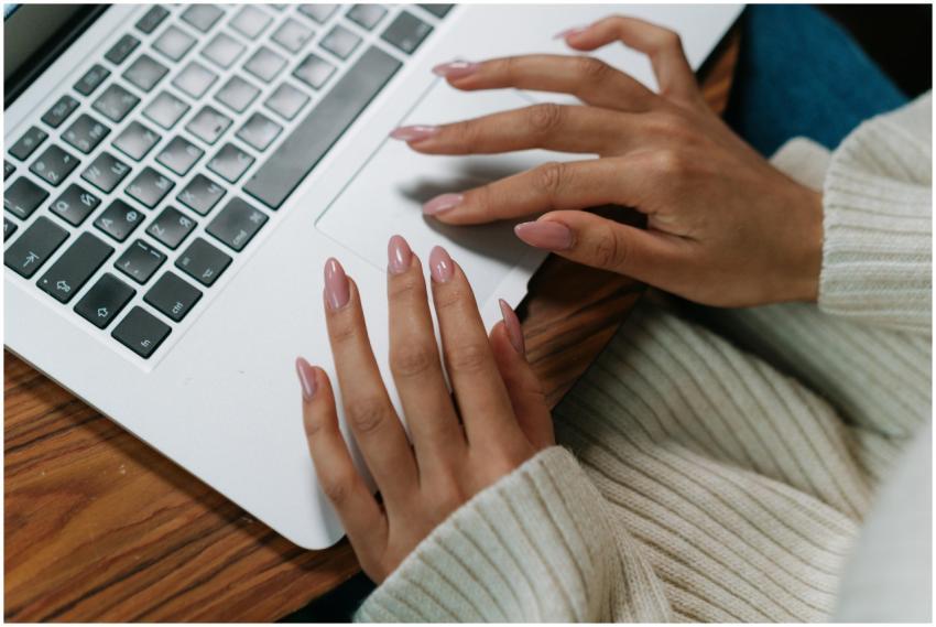 A close-up view of hands typing on a laptop keyboa