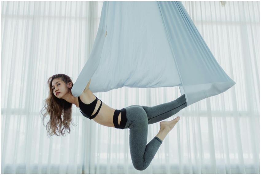 A woman practicing aerial yoga indoors on a hammoc