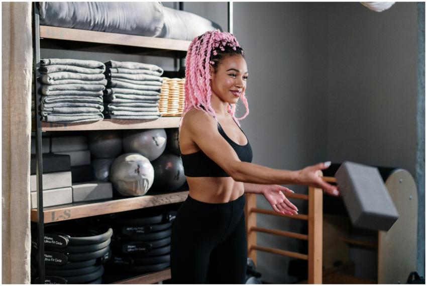 A fit yoga instructor with pink hair teaches in a