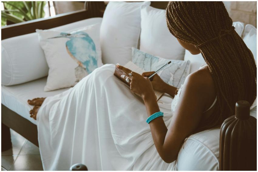 An African American woman in a white dress writing