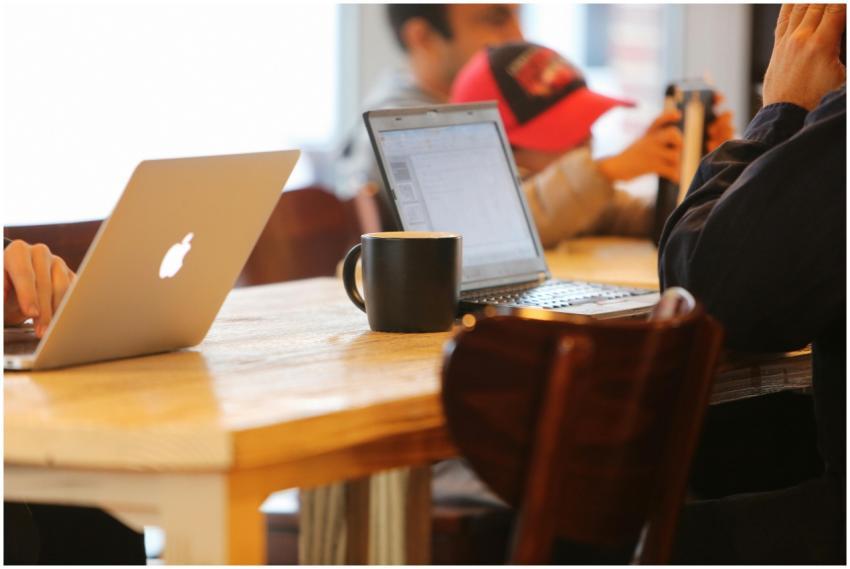 Group working in a cozy cafe with laptops and coff