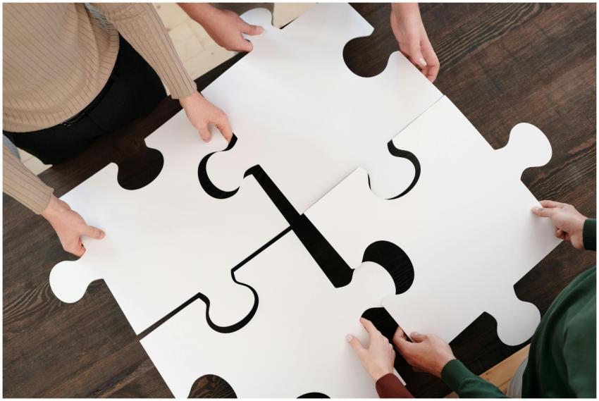 Group collaborating on assembling large puzzle pie