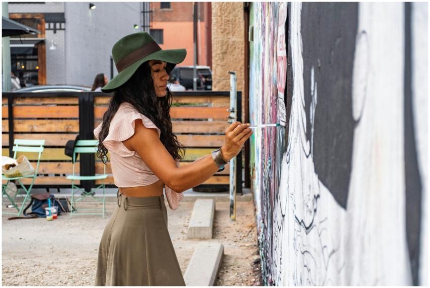 Woman artist painting a mural on an urban street w