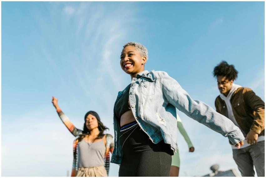 Group of diverse friends dancing outdoors in denim