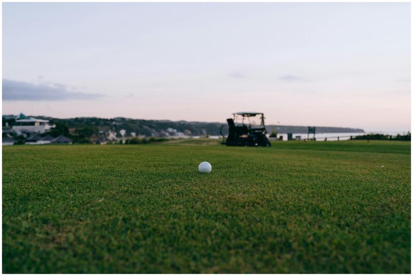 Golf ball on a scenic course with cart in the back
