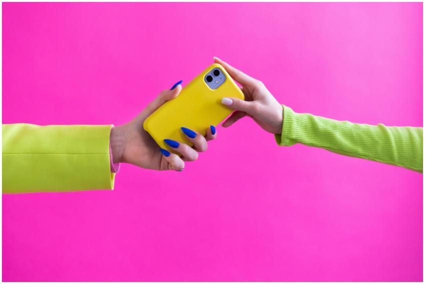 Colorful studio image of hands exchanging a yellow