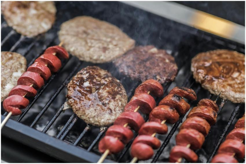 Close-up of sizzling hamburgers and sausage skewer