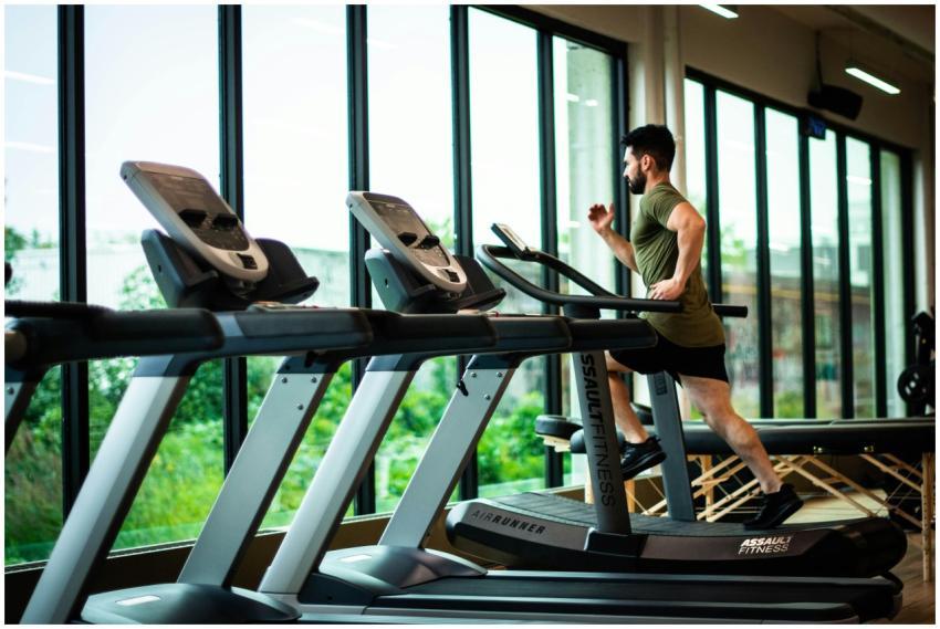 Young man workouts on treadmill in modern gym with