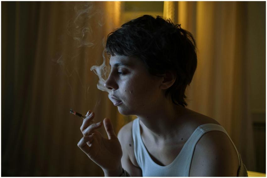 Woman with short hair smoking indoors, reflecting