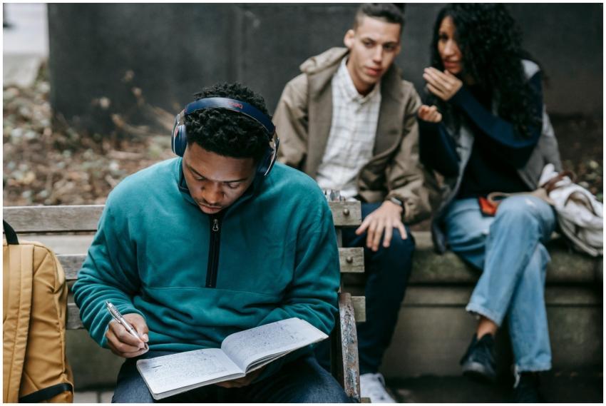 Crop young ethnic man and woman sitting on bench a