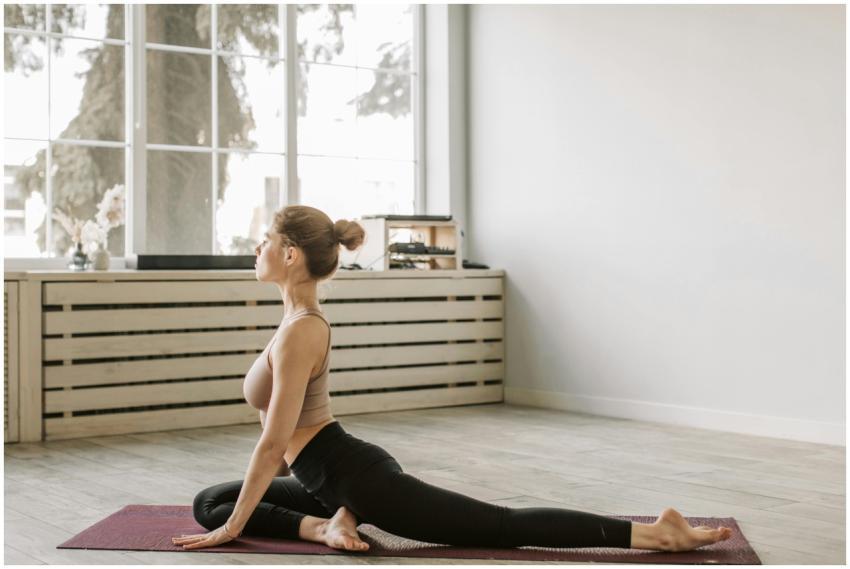 Woman practicing yoga in a sunlit room, embodying