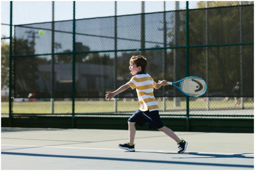 A young boy in sporty attire playing tennis on an