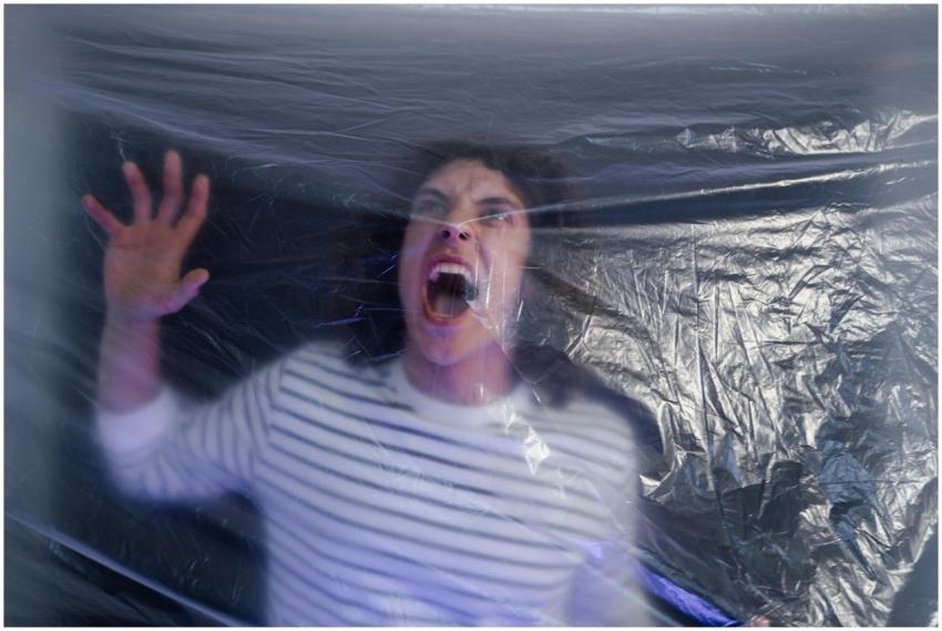 Man in striped shirt screaming behind translucent