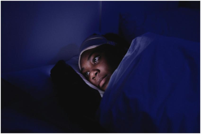 A woman lies in bed at night using her smartphone,
