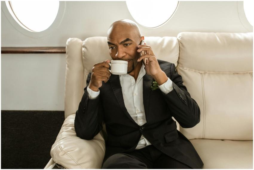 Elegant businessman seated in private jet, drinkin