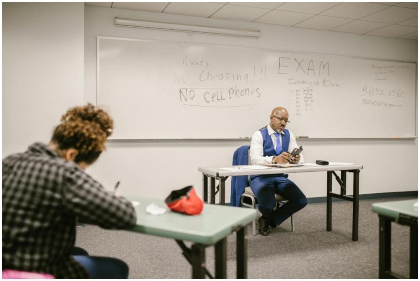 A proctor monitors an exam in a classroom setting