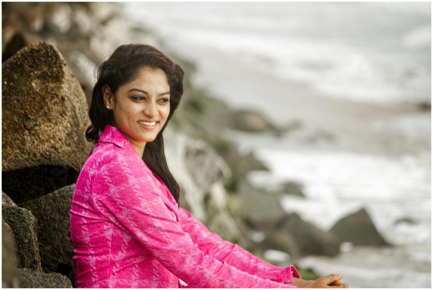 Woman in pink relaxing by seaside rocks. Serene be