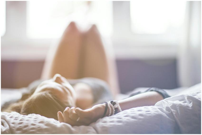 A woman lying on a bed in a peaceful, sunlit room,