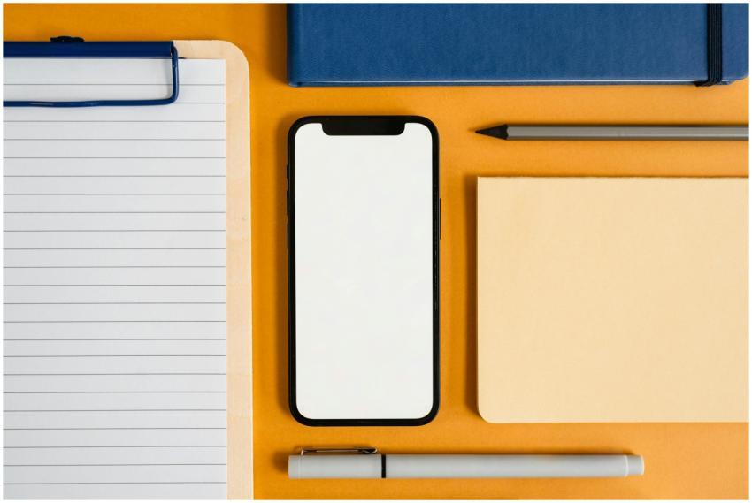 A flat lay of office supplies with a smartphone on