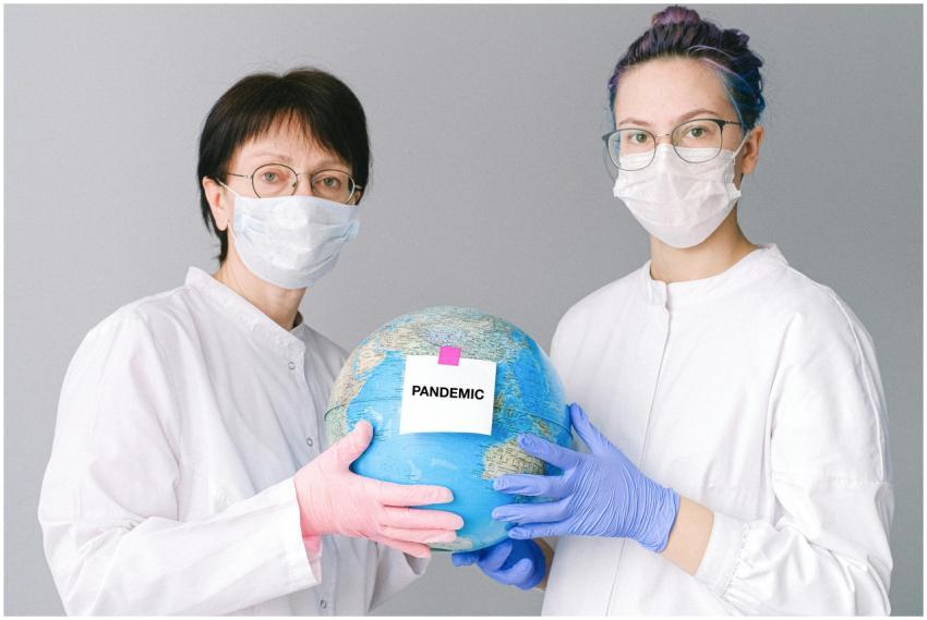Two healthcare professionals in masks hold a globe