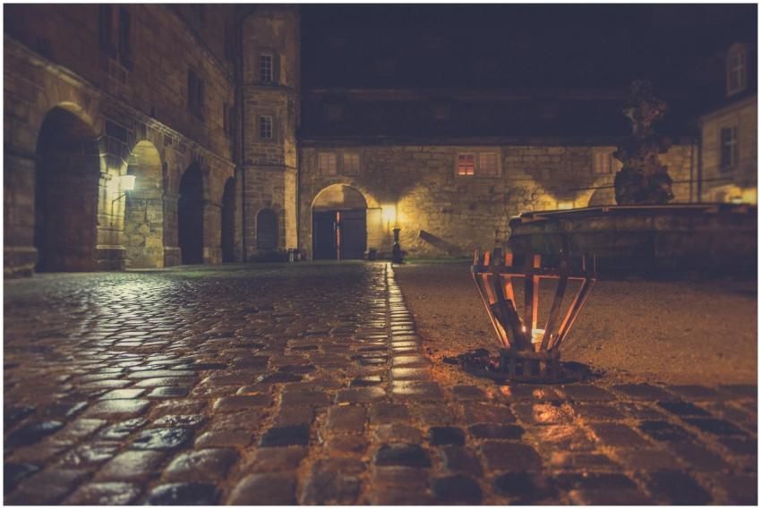 A dimly lit medieval courtyard with cobblestones a