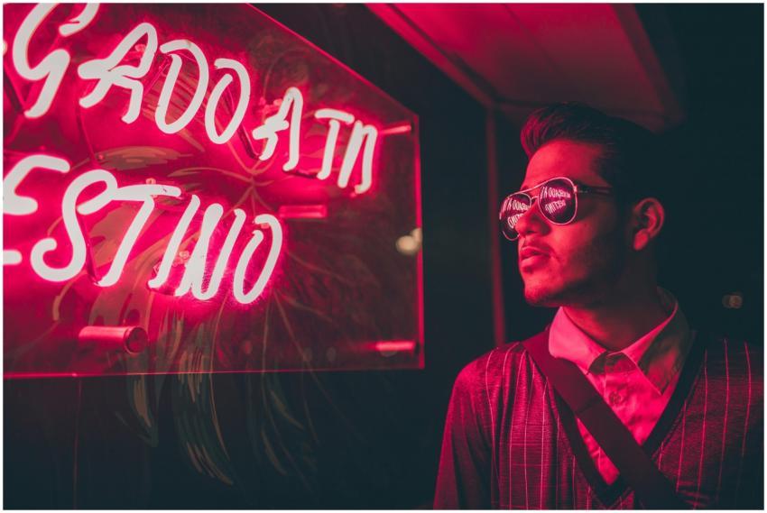 A stylish man wearing sunglasses reflects a vibran