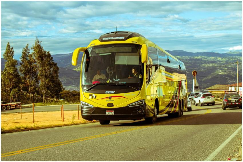 A bright yellow bus travels on a scenic mountain r