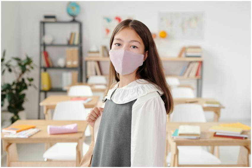 A schoolgirl in a classroom wearing a face mask, s