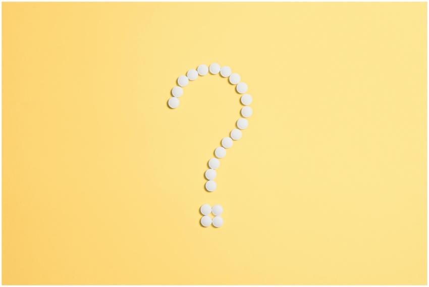 White pills arranged into a question mark shape on