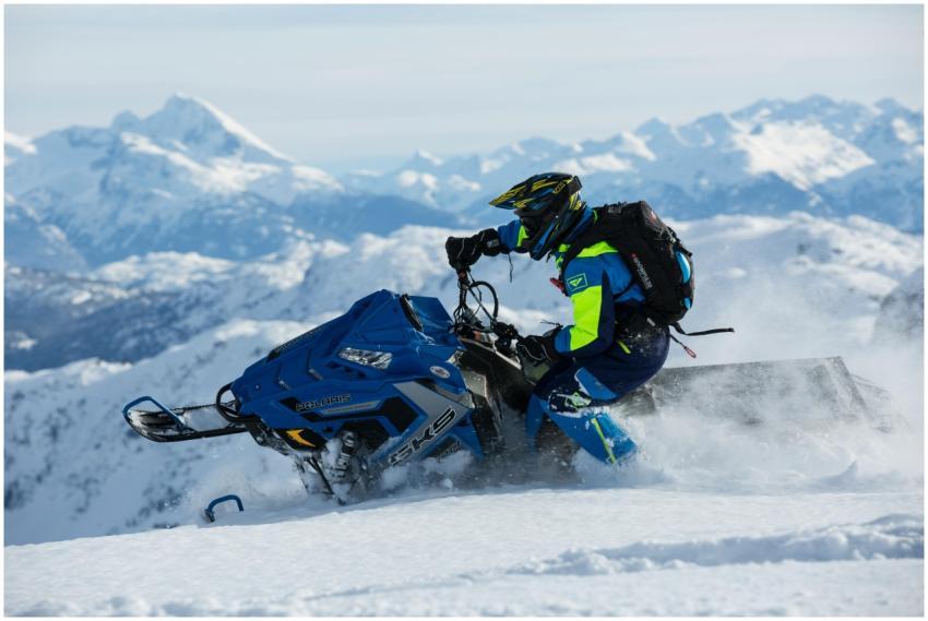 Man riding a snowmobile on snowy mountain, showcas
