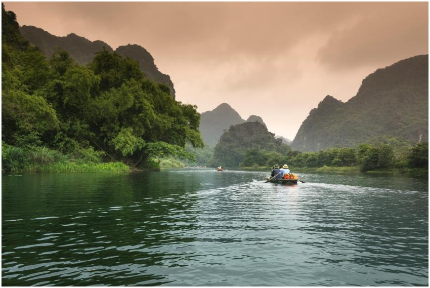 Two people rowing a boat through a serene river su