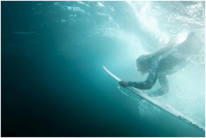 Dynamic underwater shot of a woman surfing at Bron