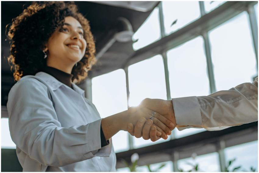 A smiling woman with curly hair shaking hands in a