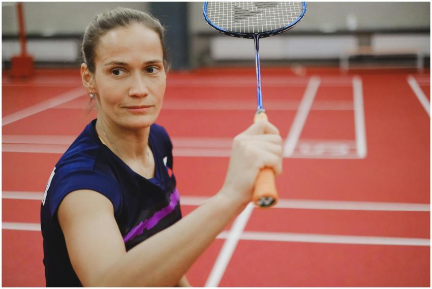Focused female badminton player ready to hit, on a