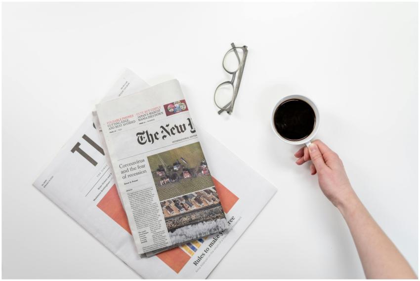 Top view of a coffee cup, newspapers, and eyeglass