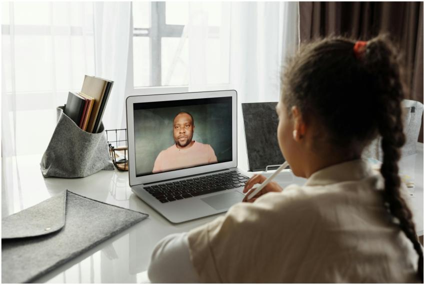 Child attending an online lesson at home via lapto