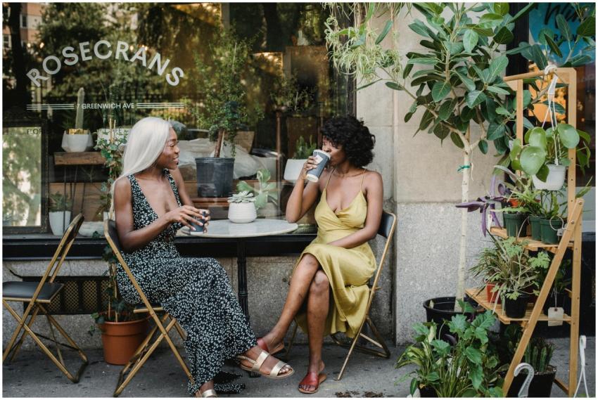 Two women sit at an outdoor café enjoying coffee s