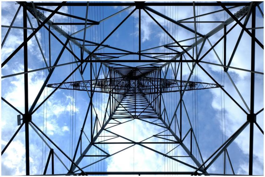 Looking up at a steel power pylon against a bright