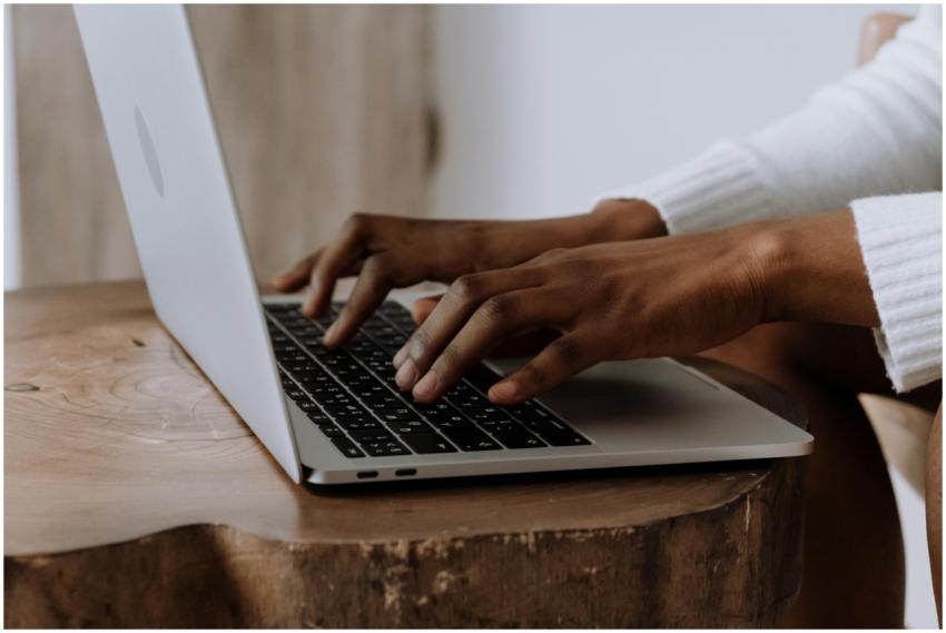 Hands typing on a laptop in a cozy indoor setting,