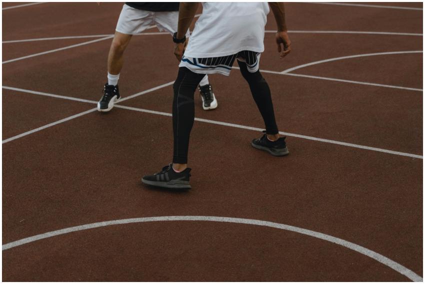 Two athletes intensely playing basketball outdoors