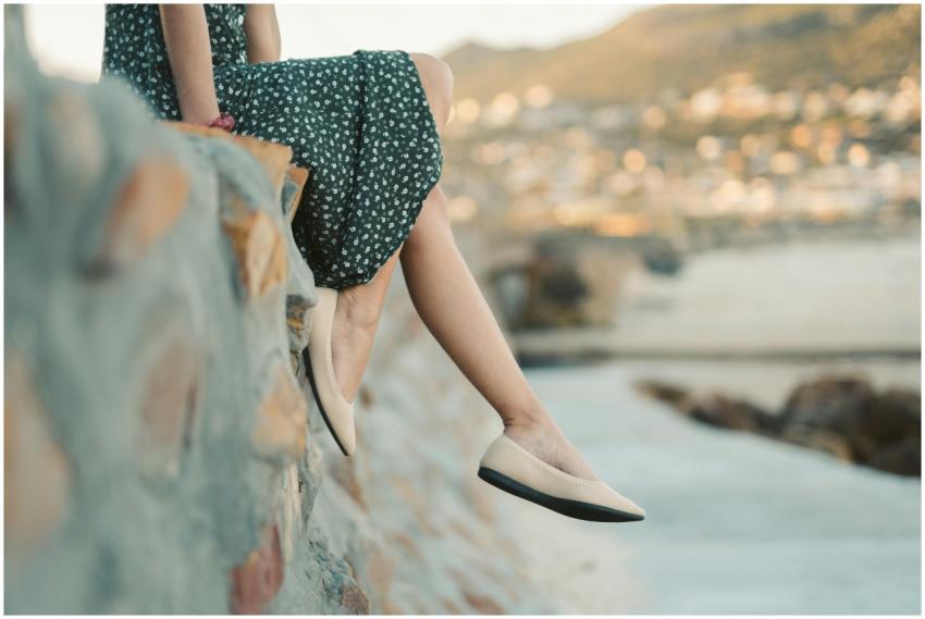 A woman sitting by the beach wearing a floral dres