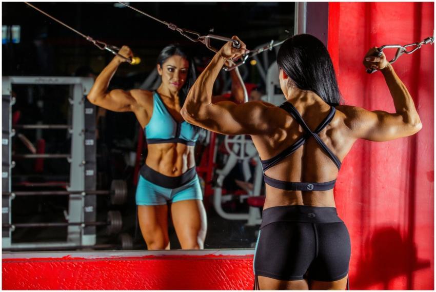 Strong female bodybuilder doing cable workout in a