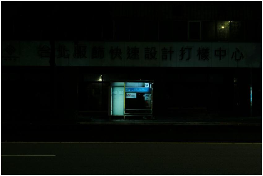 A dimly lit bus stop on a deserted street at night